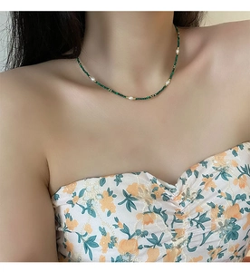 Detail of necklace with green malachite beads and freshwater pearls on model