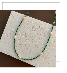 Detailed shot of malachite beads and freshwater pearls on a stone display board