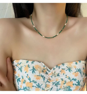 Detail of beaded malachite necklace with freshwater pearls and gold accents on model
