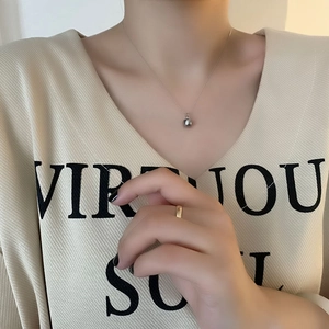 Collier élégant avec pendentif pomme dorée et chaîne à billes argentée porté par un mannequin