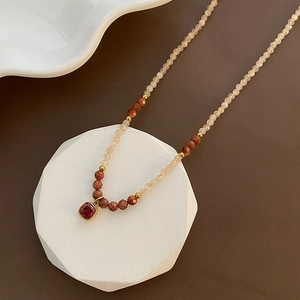 Natural stone beaded necklace featuring a red gemstone pendant on a white geometric stand