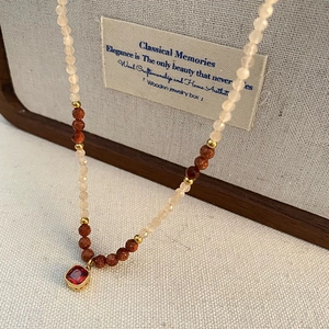 Vintage beaded necklace with natural stones and red square gemstone pendant on wooden stand
