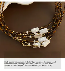Gros plan du collier à plusieurs rangs avec perles baroques, œil de tigre et acier titane