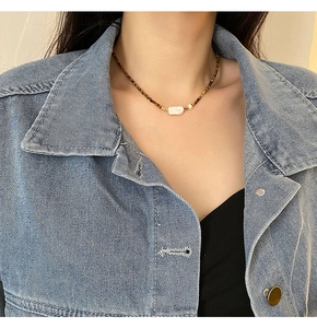 Gros plan du collier en perles baroques et pierres d'oeil de tigre sur un mannequin