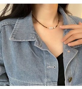 Collier en perles baroques et œil de tigre porté au cou pour un style vintage chic