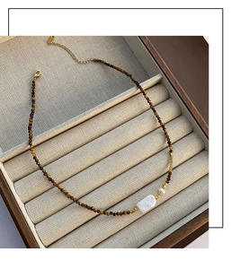 Vue macro des perles en œil de tigre et collier de perles baroques sur présentoir