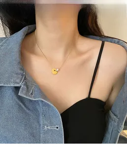 Close-up of a gold coin and pearl pendant necklace on a model wearing a denim jacket