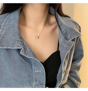 Close-up of a titanium steel gold coin necklace with a white pearl on a female model
