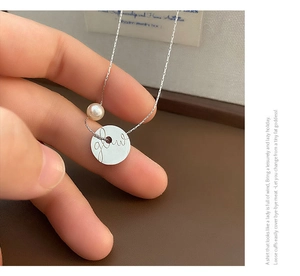 Detailed macro view of silver coin pendant with glow engraving and white pearl accent