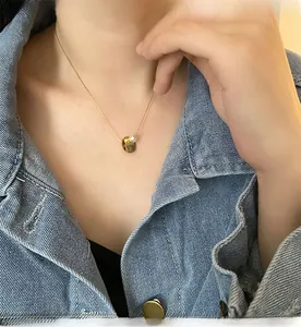 Detailed shot of a gold coin pendant with white pearl on a titanium steel necklace