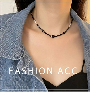 Close-up of black beaded necklace with white pearls and gold accents on model neck