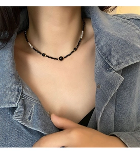 Detail of elegant black beaded necklace with white pearls on model wearing denim