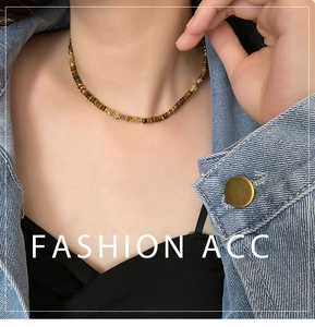 Detailed close-up of tiger eye stone beaded necklace on a model wearing denim jacket
