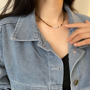 Collier en perles de nacre baroque et œil de tigre porté par un mannequin sur jean
