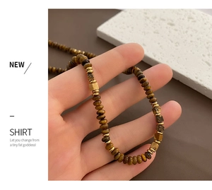 Close-up of tiger eye stone necklace with golden metallic spacer beads on stone