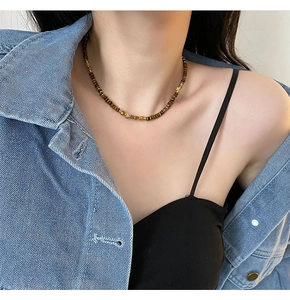 Detail of 4mm tiger eye beaded necklace with gold spacers worn by model on neck