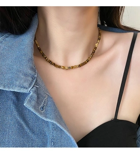 Detailed shot of tiger eye beaded necklace with gold metal accents on female model