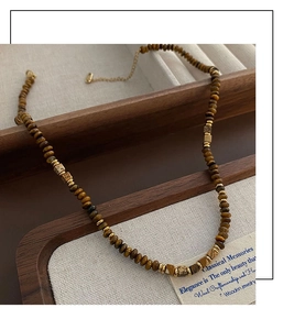 Detailed macro view of vintage tiger eye beaded necklace with gold accents and lobster clasp