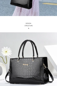Détail de sac à main noir à motif crocodile avec des finitions métalliques dorées chic