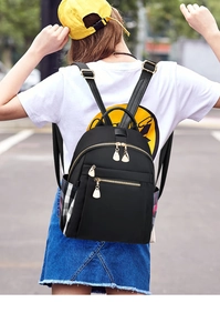 Detail of a mini black nylon backpack with golden zippers and checkerboard side pocket