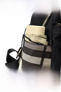 Detail of black oxford backpack side pocket with classic plaid pattern and gold hardware