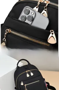 Detail of black nylon backpack featuring gold zippers and classic plaid pattern straps