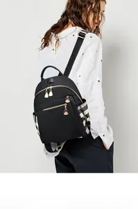 Detail of black oxford backpack showing side pocket with checkerboard pattern and gold zippers
