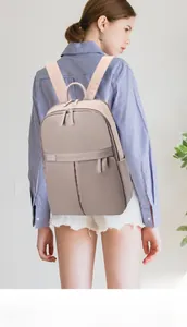 Rear view of a large taupe waterproof travel backpack shown on a female model