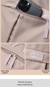 Detail of pink nylon backpack showing a smooth dual zipper and embossed leather logo