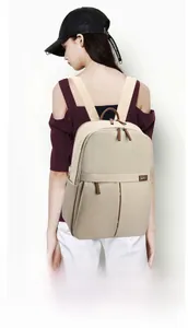 Detail of beige travel backpack featuring a luggage strap for suitcase attachment