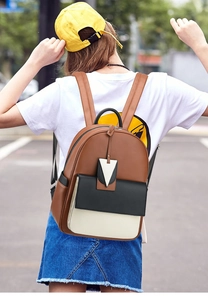 Gros plan du sac à dos en cuir tricolore avec un pendentif triangulaire décoratif