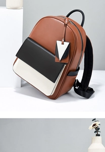Détail du sac à dos en cuir bicolore avec rabat noir et breloque décorative triangulaire