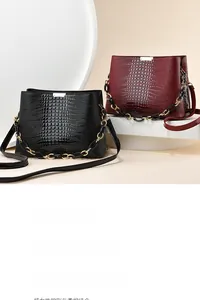 Detail of embossed crocodile texture leather handbags with decorative gold chain straps