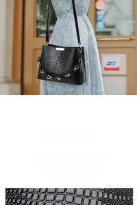 Detail of premium black cowhide leather with crocodile texture and gold hardware on handbag