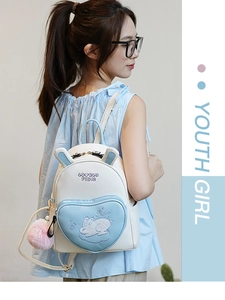 Close-up of mini backpack featuring rabbit embroidery and a pink pompom charm pendant