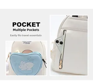 Detail of white mini backpack showing a blue heart pocket with rabbit embroidery
