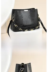 Detailed view of black embossed crocodile texture and elegant gold-toned chain on the handbag