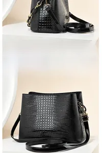 Detail view of black crocodile pattern faux leather handbag with golden metal hardware