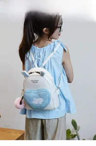 Detail of cute mini backpack with bunny ears, heart pocket and plush pendant on model