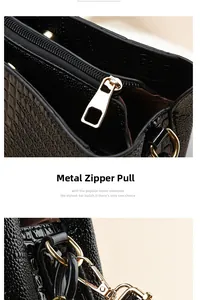 Close-up of golden metal zipper and hardware on black embossed leather handbag