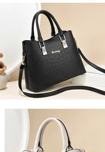 Close-up of crocodile pattern leather texture and golden metal logo on the handbag