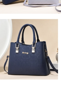 Macro detail of dark blue leather bag featuring embossed C pattern and golden metal logo