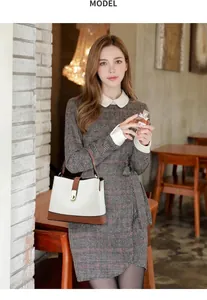 Detalle de bolso cubo bicolor con cierre dorado y vestido de lana a cuadros gris