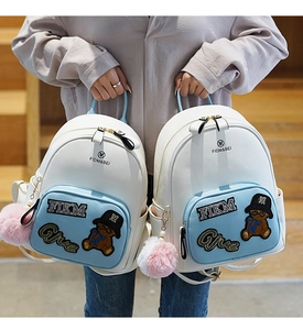 Close-up of mini backpack featuring cute cartoon bear patch and soft pompom charm