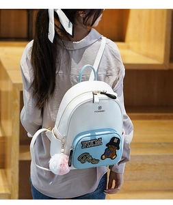 Detailed close-up of a mini backpack featuring a plush ball charm and bear pattern design