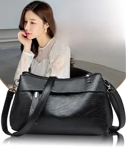 Detail of soft black patent leather crossbody bag with silver metal zipper and hardware