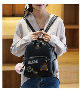 Detail of mini black PU leather backpack with cartoon bear embroidery and fluffy pompom