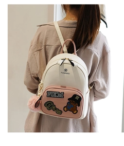 Close-up of mini cartoon bear backpack with plush pendant worn by a model