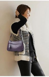 Detail shot of a dark purple leather shoulder bag with a stylish metal ring buckle