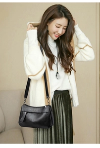 Detail of minimalist black soft leather crossbody bag with adjustable textile shoulder strap